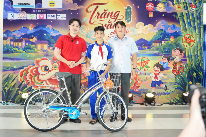Học sinh nhận xe đạp từ ban tổ chức trên sân khấu chương trình Trăng rằm cho em