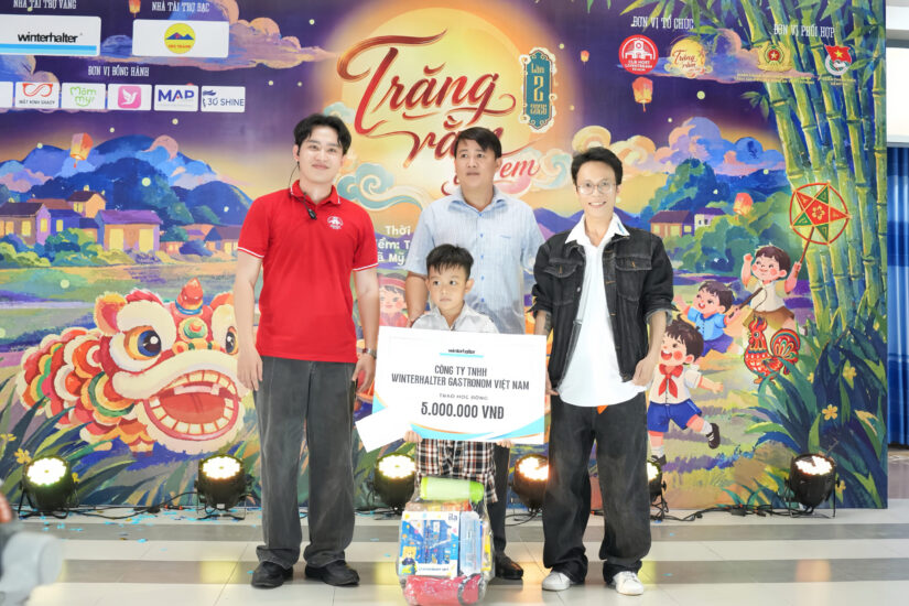Đại diện nhà tài trợ trao bảng tượng trưng tám triệu đồng trước phông nền Trăng rằm cho em