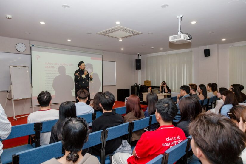 Diễn giả cầm micro mở đầu workshop Beyond the voice trong hội trường có màn chiếu