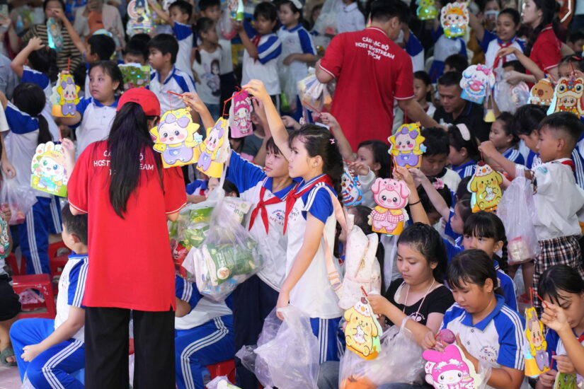 Thành viên CLB phát lồng đèn cho các em học sinh đang giơ tay nhận