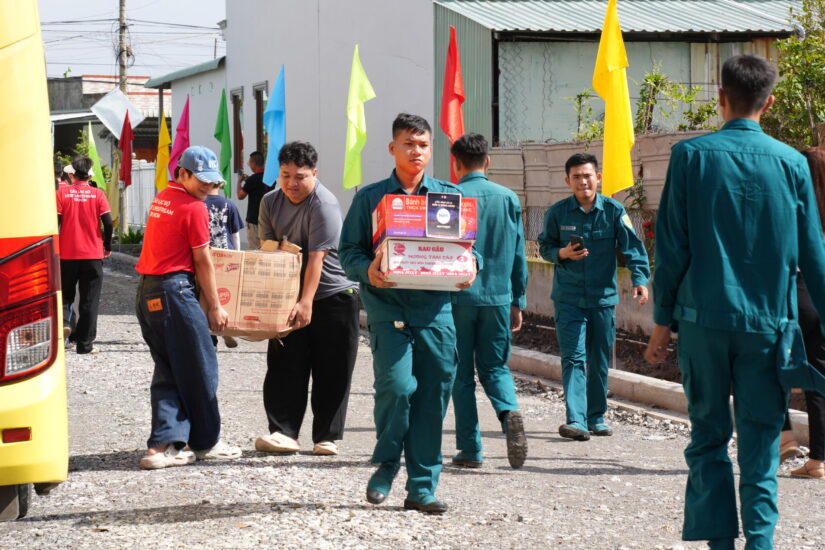 Thành viên CLB và dân quân địa phương cùng khiêng thùng quà xuống xe