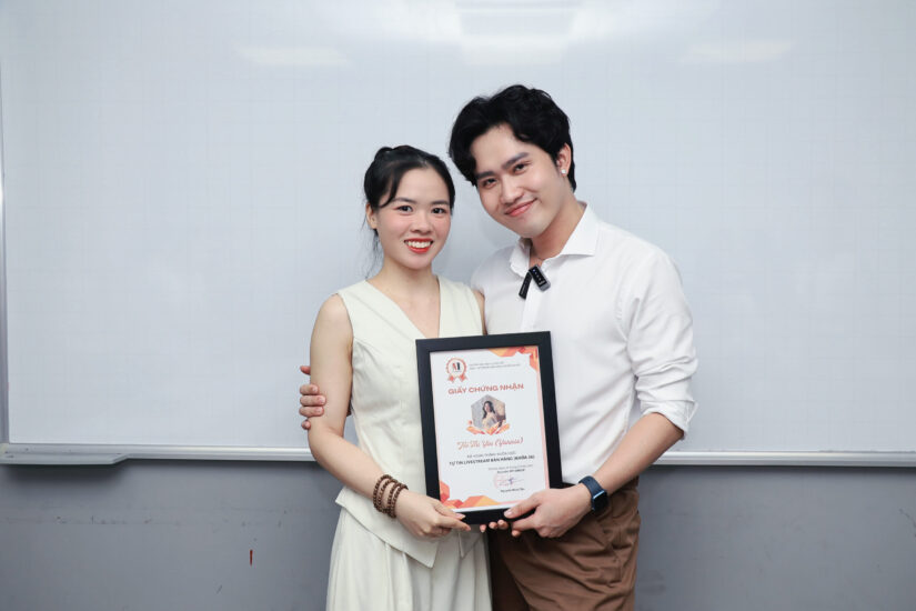 Hai học viên cầm giấy chứng nhận chụp ảnh kỷ niệm trong phòng học LIVE Academy